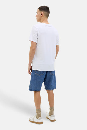 Short en jean bleu moyen de JACK & JONES JEANS INTELLIGENCE, vue arrière d'un homme avec un t-shirt blanc, des chaussettes beiges et des baskets.