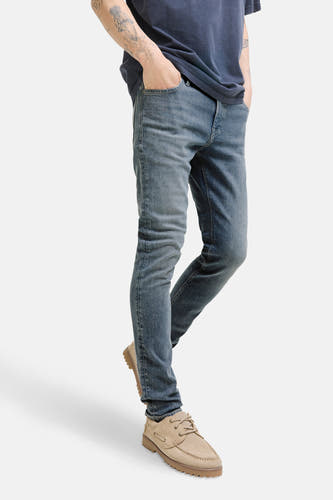 Jean slim de JACK & JONES JEANS INTELLIGENCE en denim gris moyen, porté avec un t-shirt bleu et des chaussures en cuir de mouton.