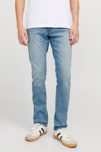 Jean slim fit bleu clair de JACK & JONES JEANS INTELLIGENCE, porté avec un T-shirt blanc et des baskets blanches.