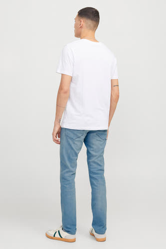 Jean slim fit bleu clair de JACK & JONES JEANS INTELLIGENCE, avec une légère usure et des baskets blanches.