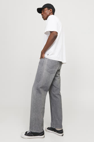 Jean de denim clair et large de JACK & JONES JEANS INTELLIGENCE, porté avec un modèle en t-shirt blanc et casquette noire.