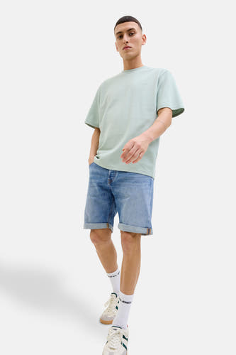 Jean court en denim bleu clair de JACK & JONES JEANS INTELLIGENCE, avec des poches surmontées, porté avec des chaussettes blanches et des baskets crème.