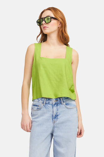 Blouse verte sans manches de JJXX, avec une ligne d'épaules carrée et portée avec un jean.