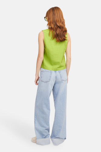 Achterkant van een vrouw in een groene top en wijde jeans.