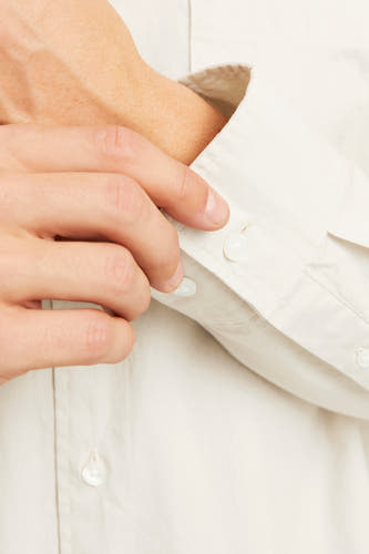 Chemise écru à longues manches de PREMIUM by JACK & JONES, détail d'une main fermant un nœud.
