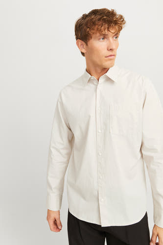 Chemise écru à manches longues de PREMIUM by JACK & JONES, avec une poche po po et un pantalon noir.