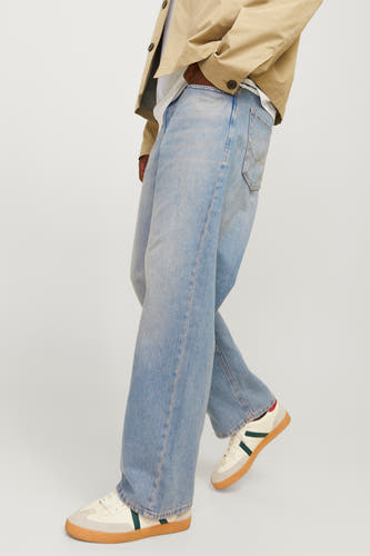 Jeans larges en denim bleu clair de JACK & JONES JEANS INTELLIGENCE, portées avec une veste beige et des baskets blanches.