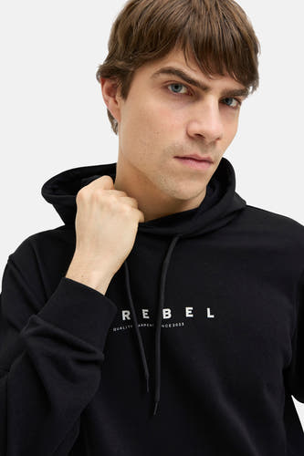 Sweatshirt noir à capuche de JJREBEL, avec lettres blanches "REBEL" sur la poitrine, porté par un homme.