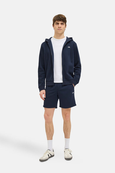 Short bleu marine de JJREBEL, combiné avec un T-shirt blanc, un gilet zippé bleu marine, des chaussettes blanches et des baskets.