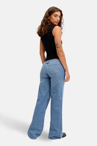 Blauw denim flared jeans van JJXX, gezien van achteren met een zwarte top en donkere schoenen.
