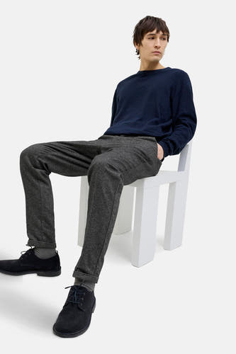 Chino gris de JACK & JONES JEANS INTELLIGENCE, porté avec un pull bleu foncé et des chaussures noires, assis sur une chaise blanche.