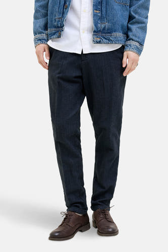 Jean chino bleu de JACK & JONES JEANS INTELLIGENCE, associé à des bottes en cuir marron, une blouse blanche et un blouson de travail.