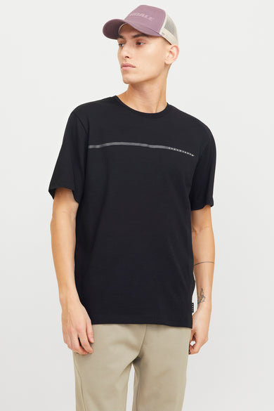 T-shirt noir à manches courtes de CORE par JACK & JONES, avec une rayure horizontale et porté avec un pantalon beige et un chapeau.