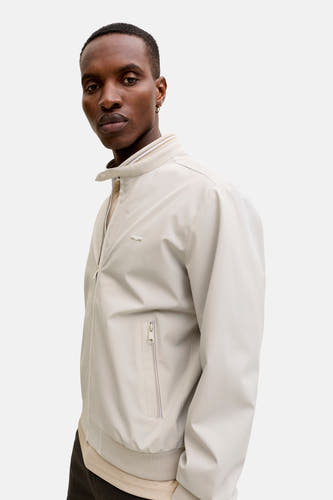 Veste courte beige de PREMIUM by JACK & JONES avec col montant rayé, fermeture à glissière et logo sur la poitrine.