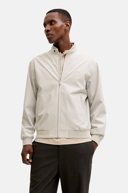 Manteau court beige de PREMIUM by JACK & JONES avec col montant rayé, fermeture à glissière, poignets côtelés et deux poches zippées.