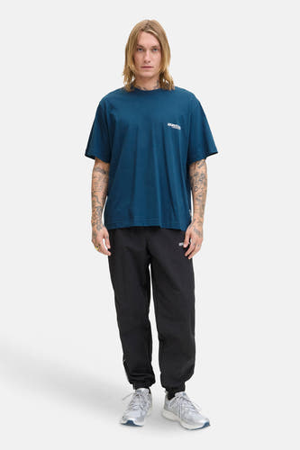 T-shirt bleu à manches courtes de CORE BY JACK & JONES, avec logo, porté avec un short d'entraînement noir et des baskets argentées.