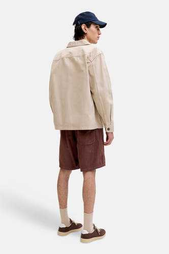 Bruine corduroy shorts van JACK & JONES JEANS INTELLIGENCE, zijprofiel, met zak, gedragen met beige overhemd en blauwe pet
