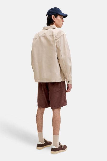 Bruine corduroy shorts van JACK & JONES JEANS INTELLIGENCE, zijprofiel, met zak, gedragen met beige overhemd en blauwe pet
