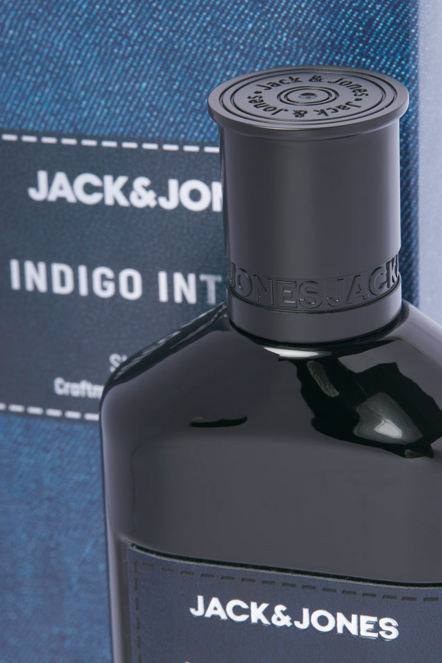 Blauwe parfum van ACCESSORIES BY JACK & JONES, met dop met logo, en detail van de verpakking met denim textuur.
