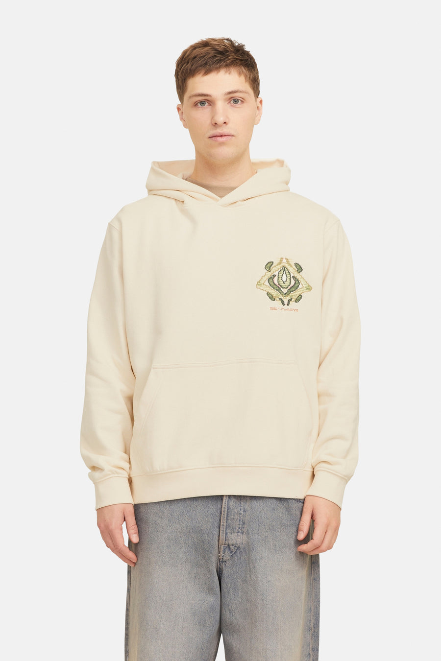 Man met beige hoodie en blauwe jeans.