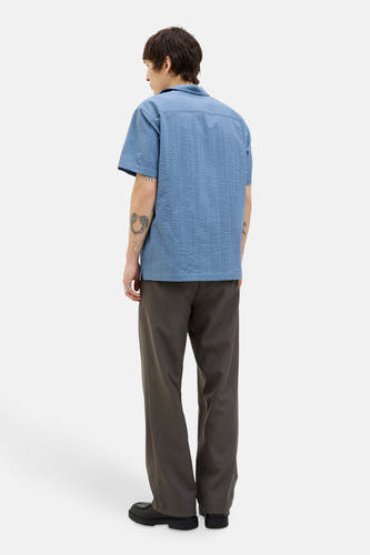 Chemise bleue à manches courtes de PREMIUM BLUE par JACK & JONES, avec une texture et portée avec un pantalon marron et des chaussures noires.