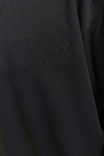 Zwart geborduurd logo op zwarte stoffen kleding.
