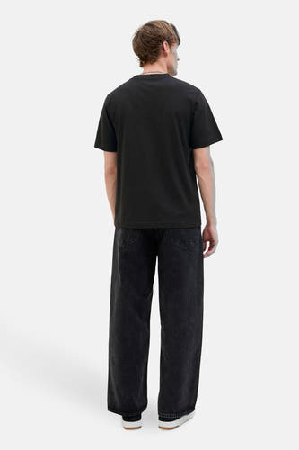 Zwart T-shirt met korte mouwen van CORE BY JACK & JONES, gezien van achteren, met wijde, donkere jeans en witte schoenen.