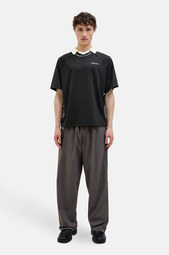 Polo noir à manches courtes de CORE BY JACK & JONES, avec col blanc et chaîne argentée.