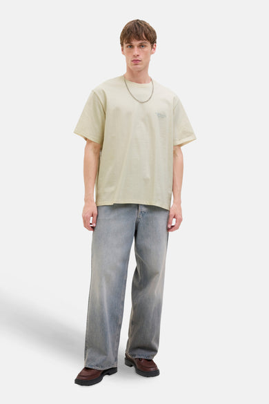 T-shirt écru à manches courtes d'ORIGINALS par JACK & JONES, avec une chaîne argentée et des jeans larges.