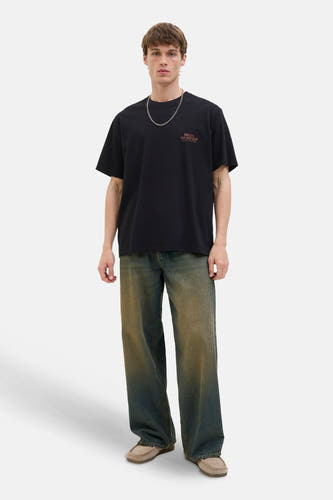 T-shirt noir à manches courtes d'ORIGINALS BY JACK & JONES, avec une chaîne argentée et des jeans bleu marine.