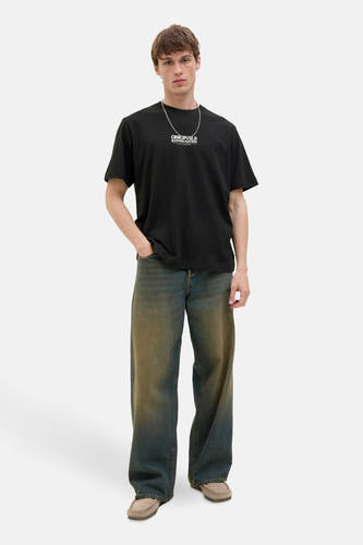 T-shirt noir à manches courtes d'ORIGINALS BY JACK & JONES, avec une chaîne argentée et une main dans la poche.