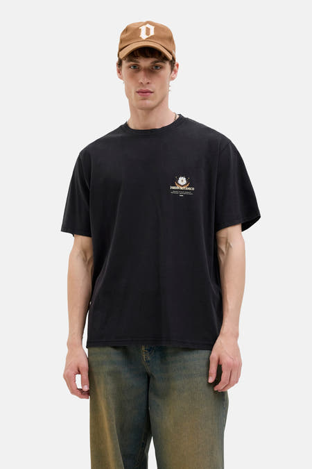 T-shirt noir à manches courtes d'ORIGINALS BY JACK & JONES, avec une petite impression sur la poitrine, porté avec un chapeau brun et des jeans.