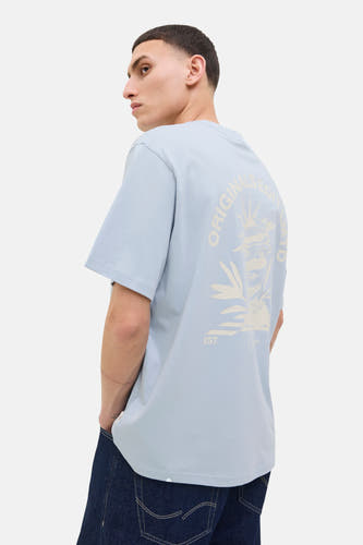 T-shirt bleu à manches courtes d'ORIGINALS BY JACK & JONES, avec une impression graphique sur le dos, porté avec des jeans foncés.