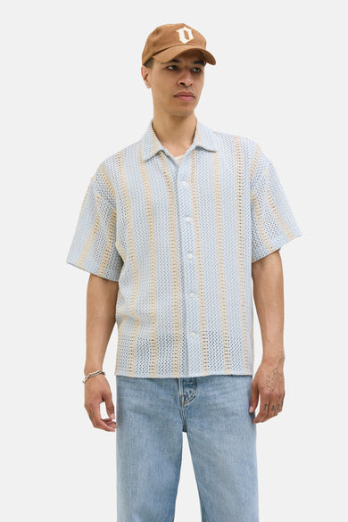Chemise bleue claire à manches courtes d'ORIGINALS BY JACK & JONES, avec un motif rayé vertical en tricot, portée avec un chapeau et une pantalon de cuir.