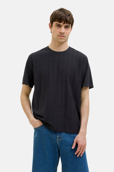 T-shirt noir à manches courtes de JJREBEL, avec une subtile texture et porté avec des jeans bleus.