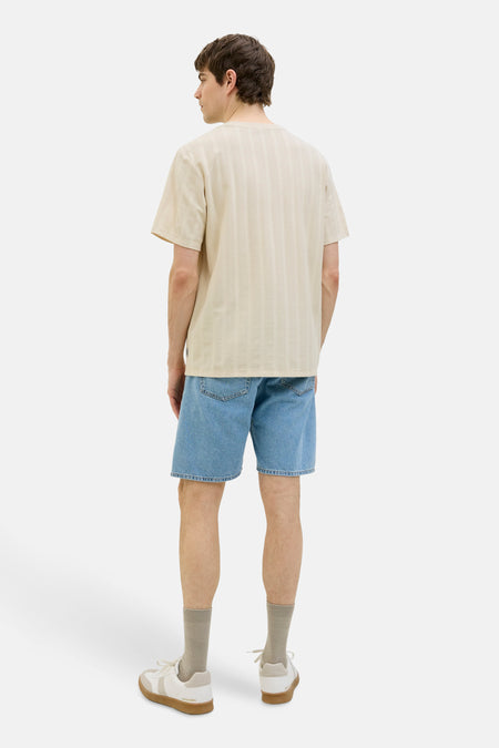 T-shirt beige à manches courtes de JJREBEL, avec des rayures verticales subtiles, associé à des shorts en denim et des baskets.