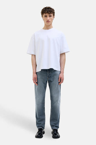 Jean tapered de JACK & JONES JEANS INTELLIGENCE en denim bleu moyen, porté avec un T-shirt blanc et des chaussures noires.