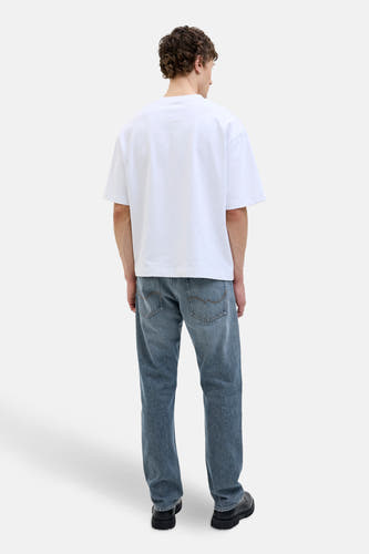 Jeanon denim bleu délavé JACK & JONES JEANS INTELLIGENCE,, en arrière-plan combiné avec un T-shirt blanc et des chaussures noires.