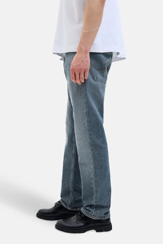 Jean tapered en denim bleu de JACK & JONES JEANS INTELLIGENCE, avec un t-shirt blanc décontracté et des chaussures noires.