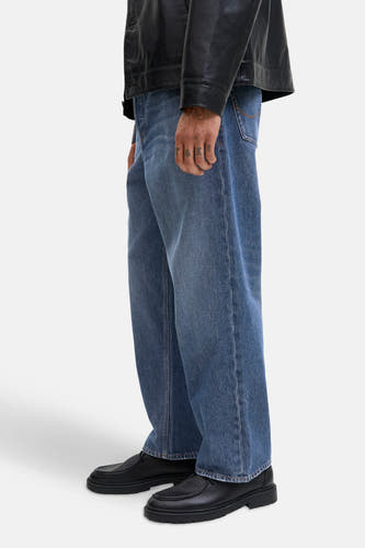 Jean bleu, large de JACK & JONES JEANS INTELLIGENCE, avec un blouson en cuir et des chaussures noires.