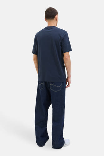 T-shirt bleu à manches courtes de CORE BY JACK & JONES, sur un modèle avec des jeans larges et des baskets blanches.