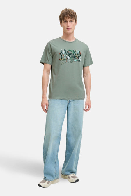 Man in groen Jack & Jones T-shirt en wijde jeans.