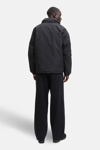 Manteau court noir de CORE par JACK & JONES, avec un chemisier rayé dessous.