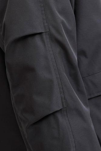 Donkergrijze jas met zakken en stiksels.