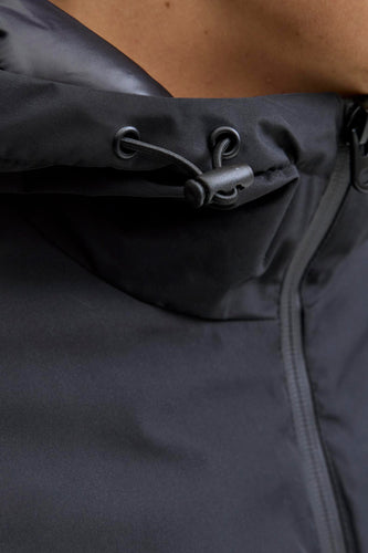 Zwarte jas met capuchon en trekkoord.