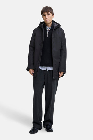 Manteau noir d'ORIGINALS BY JACK & JONES, avec capuche et porté sur un pull et un pantalon.