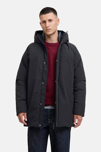 Manteau long noir d'ORIGINALS BY JACK & JONES, avec capuche et porté sur un pull rouge et des jeans foncés.
