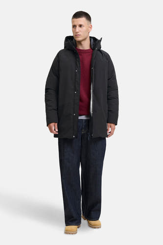 Manteau long noir d'ORIGINALS BY JACK & JONES, avec capuche, porté avec un pull rouge et des jeans larges.