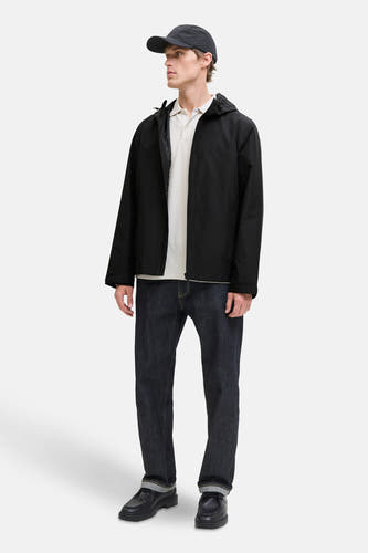 Manteau court noir d'ORIGINALS BY JACK & JONES, avec capuche, associé à une polo, des jeans et des chaussures noires.