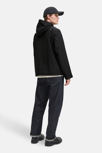 Manteau court noir d'ORIGINALS BY JACK & JONES, avec capuche et jeans noirs à poches repliées.